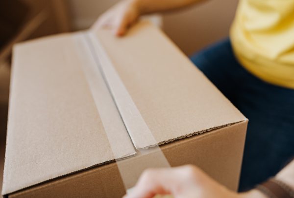 Person Sealing Cardboard Box with Packaging Tape