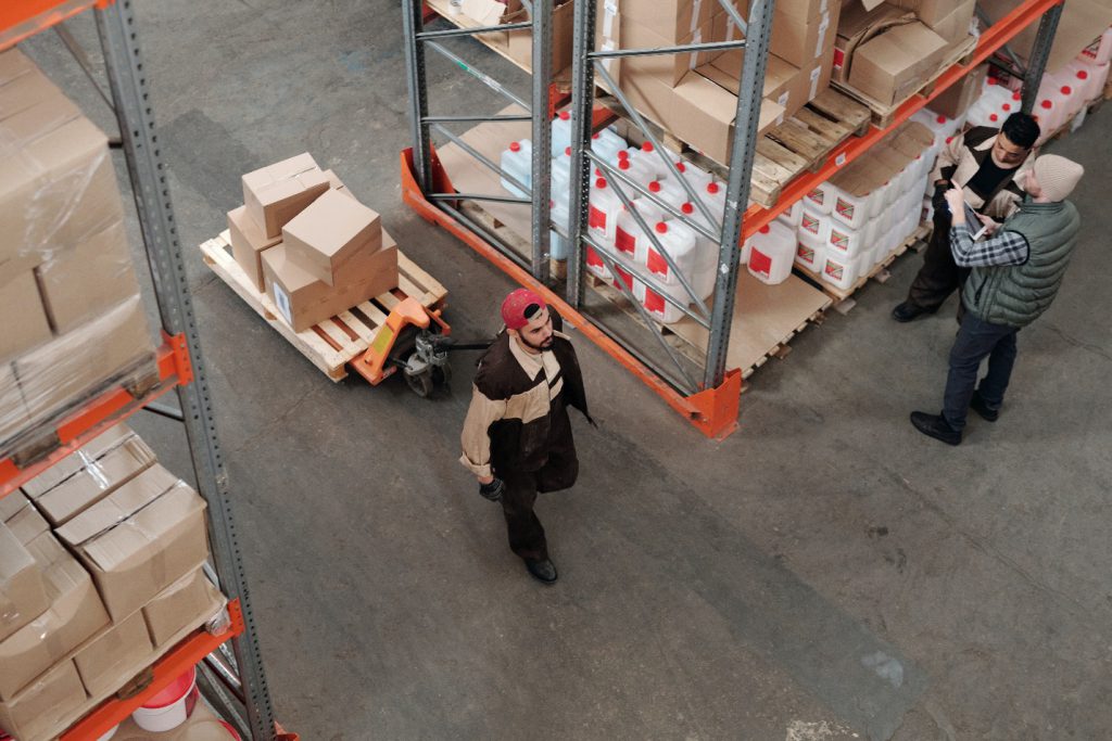 Man Transporting Packaging Boxes In Warehouse