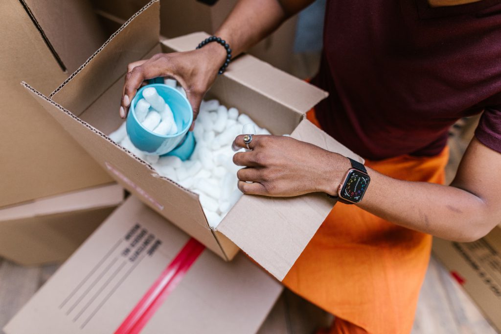 High Angle View of Person Packing Cardboard Box With Protection Foam